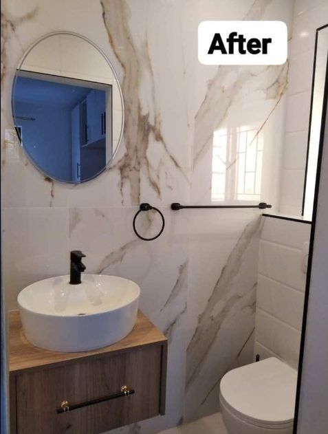 Modern bathroom with marble walls, round mirror, vessel sink and wooden vanity after plumbing work