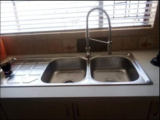 Double-basin kitchen sink with faucet and tiled backsplash after installation